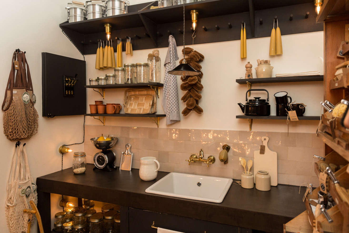 Kitchen accessories are arrayed around a concrete sink counter. The zellige backsplash tiles and brass bridge faucet are both Moroccan. The under-shelf brass sconces (€45) are a González & González design.