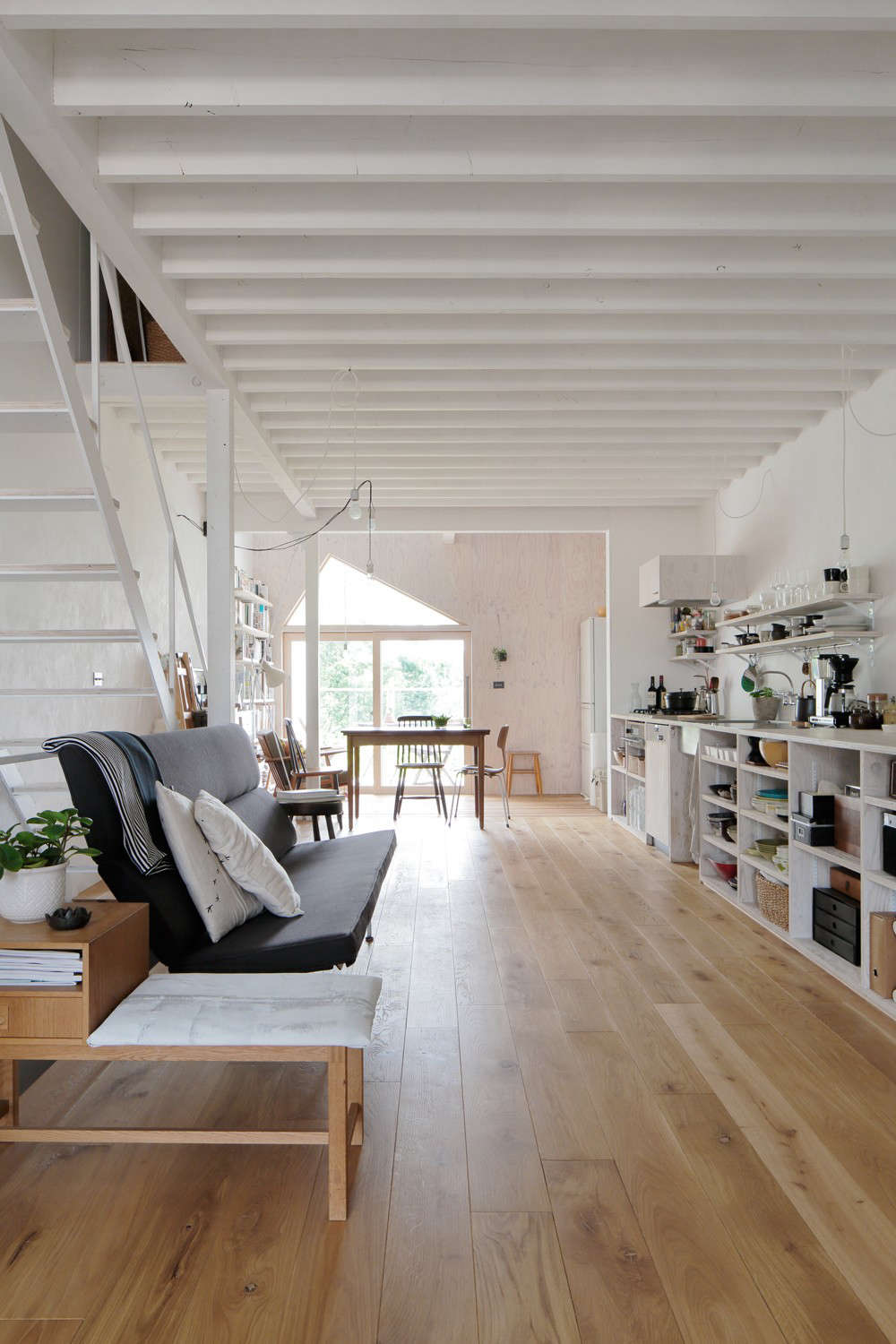 An open kitchen runs along the second floor anchored by living and dining balconies at either end.