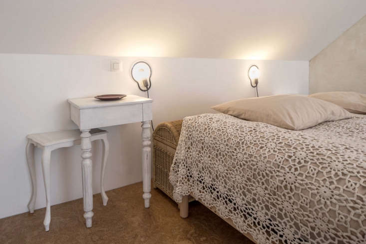 a bedroom with an antique rattan trunk, lace bedspread, droog sticky lamps, and 25