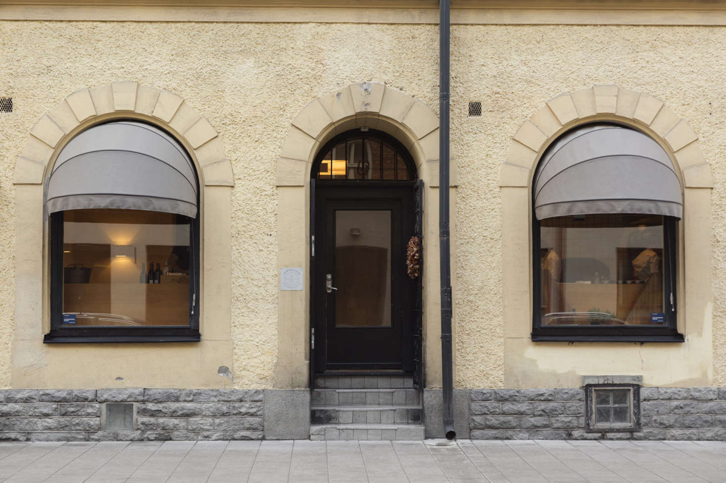 The stately exterior of Agrikultur, with muted tones and awnings. Note also: the dried-flower wreath hanging on the black front door.