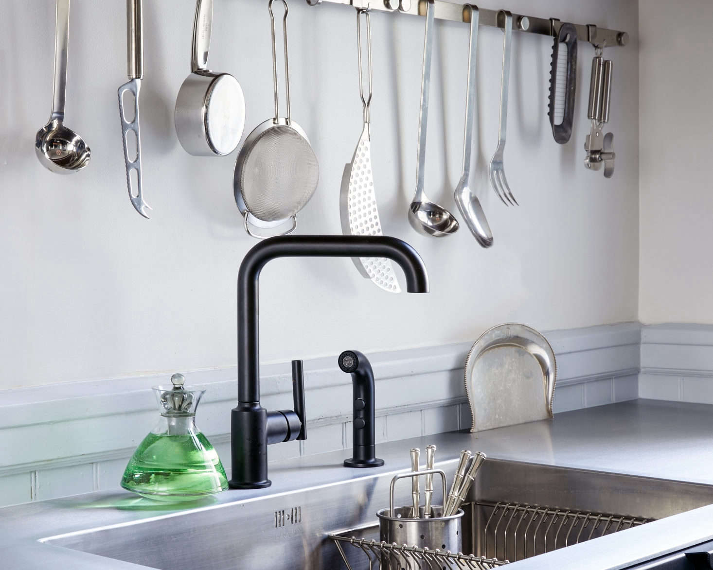 The open kitchen utensil rail is from German company Rosle and the matte black Purist Single Handle Faucet is from Kohler. 