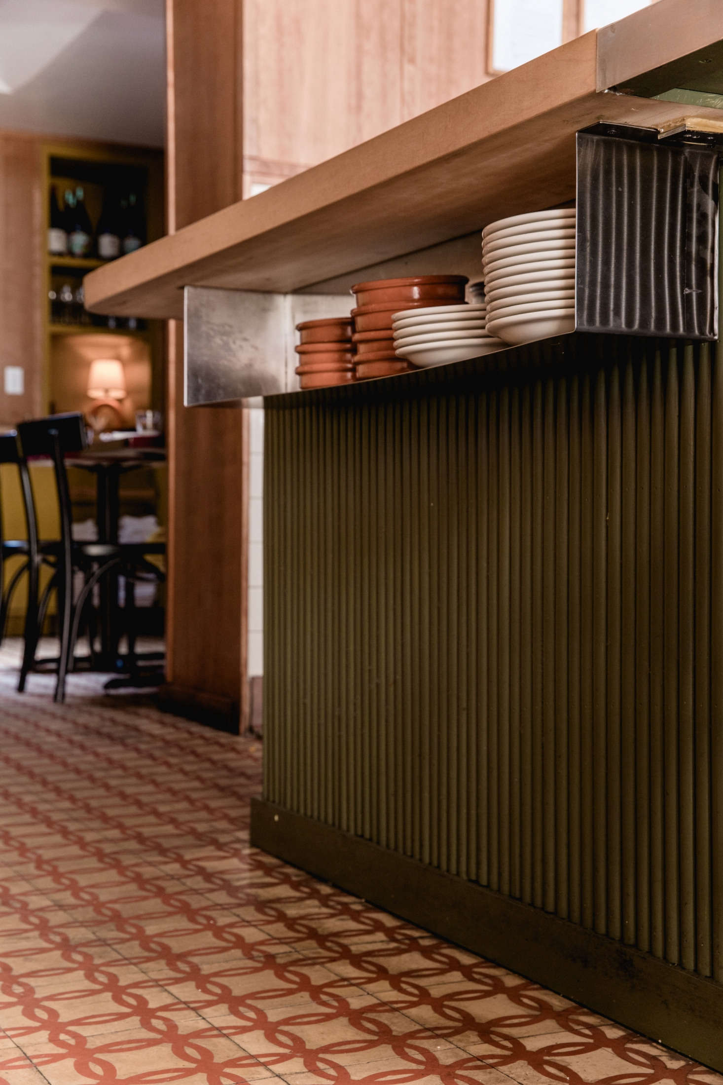 With a tight prep space, the team built storage into easy-to-access places, like this metal shelf that holds serveware underneath the bar