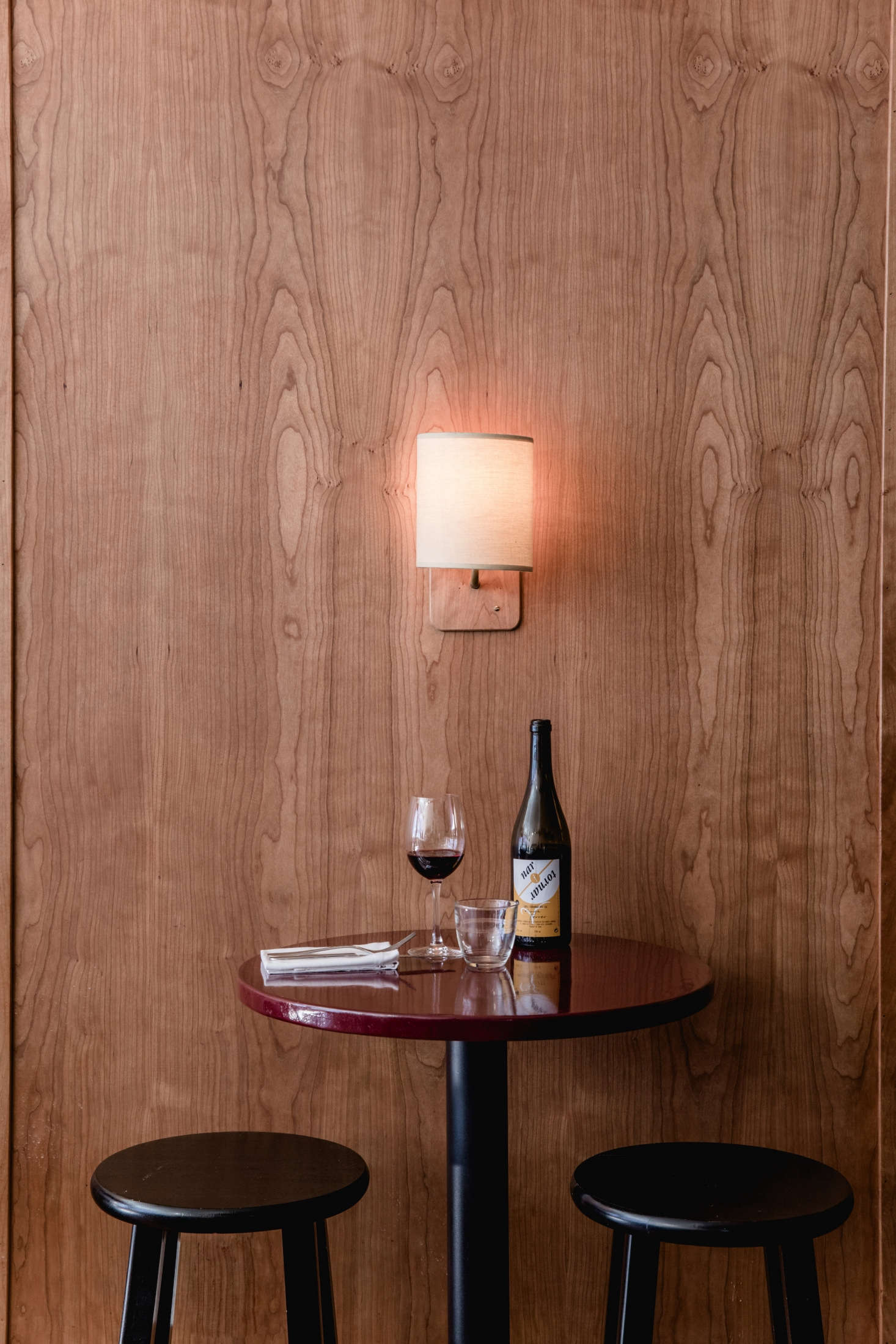 In keeping with traditional Portuguese cervecerias, the existing white walls were replaced with custom millwork—in this case, cherry—by Carver Farrell at Living Space Design. The row of banquettes was replaced with round high-tops painted in Fine Paints of Europe
