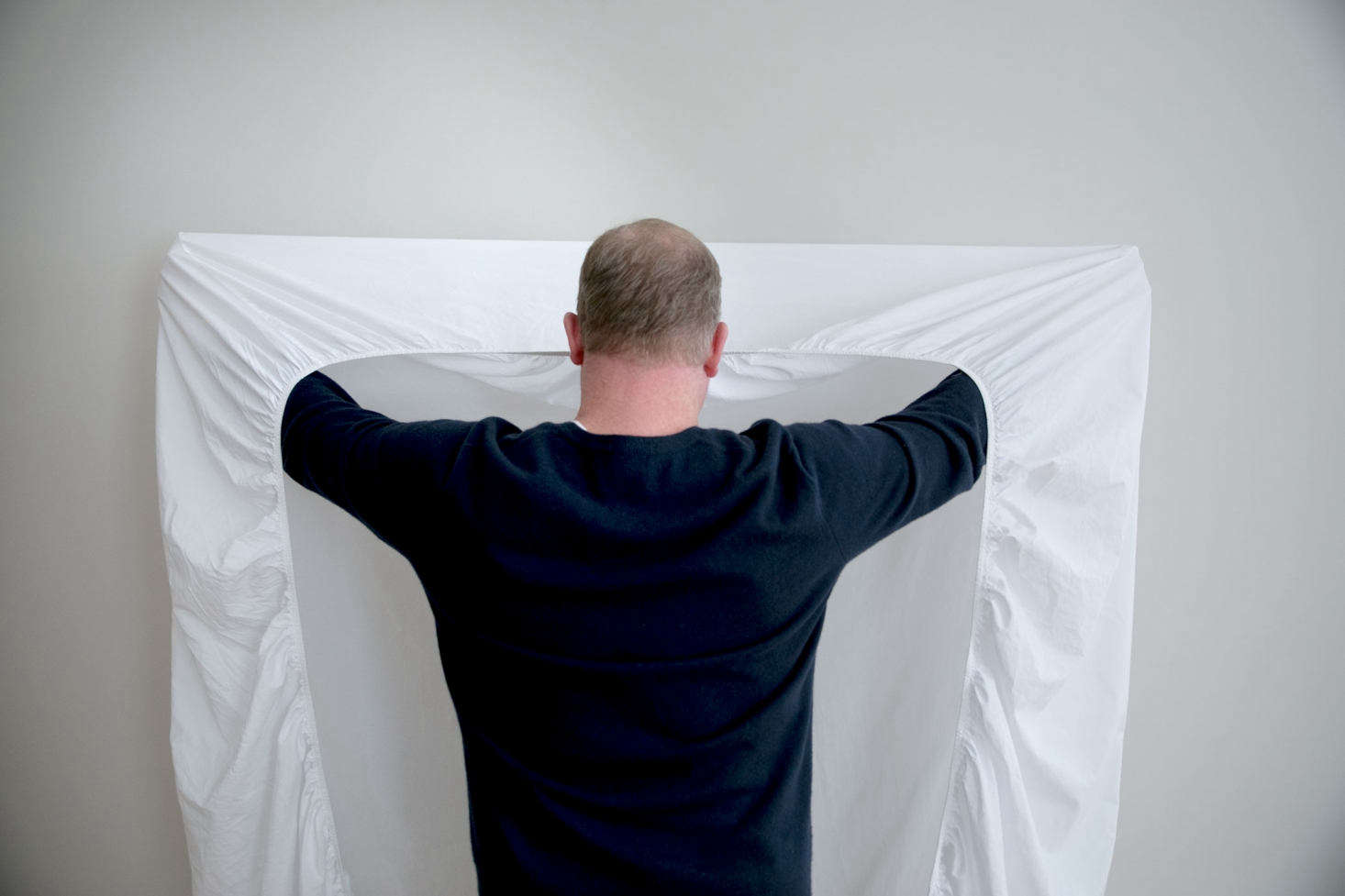 With the elastic side facing you, place your hands inside the top two corner pockets of the sheet.