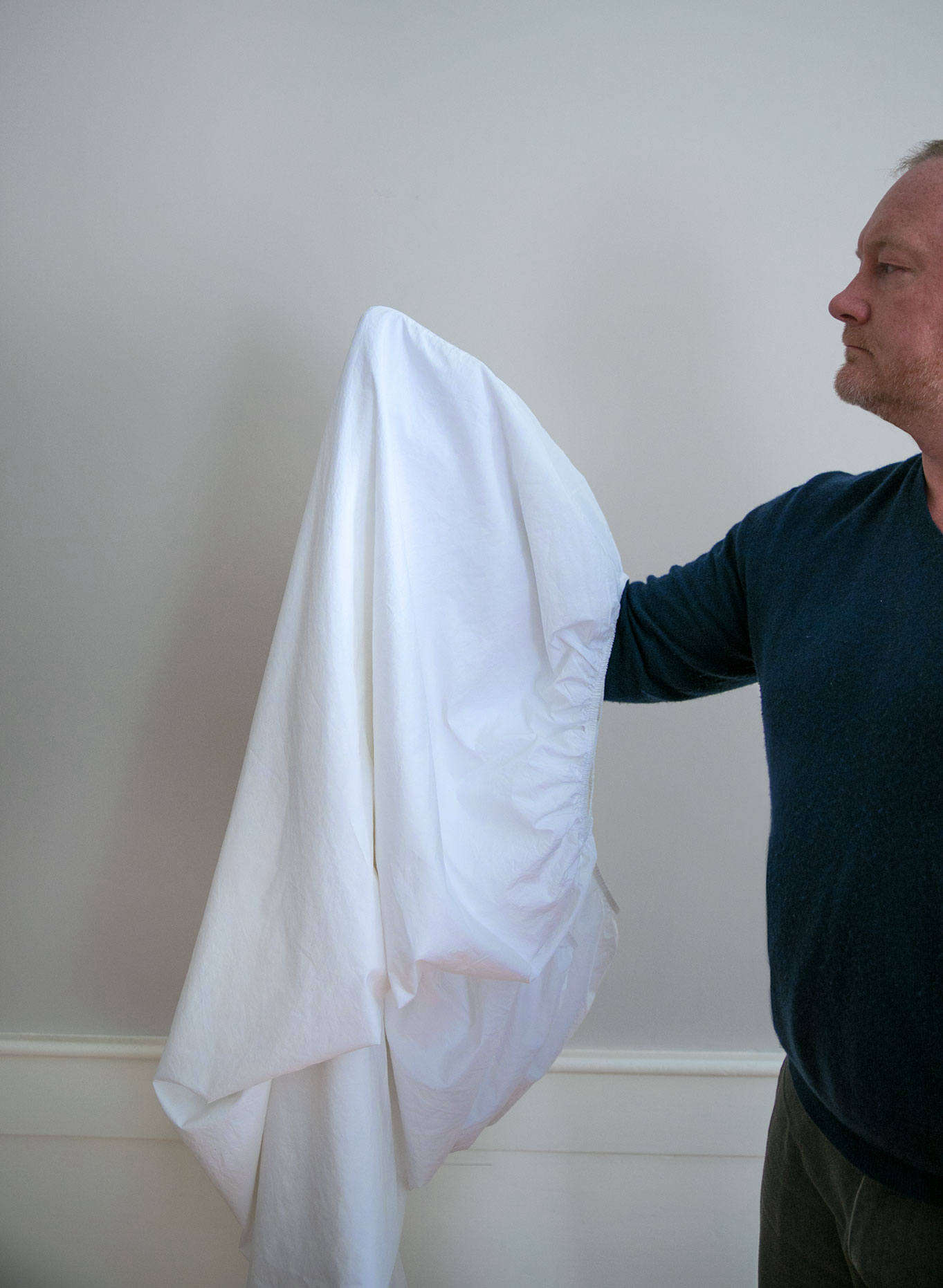 With one hand in each doubled corner pocket, repeat Step Two: Turn one of the doubled corner pockets inside out, fold the sheet in half again, and tuck this corner pocket into the corner pocket you