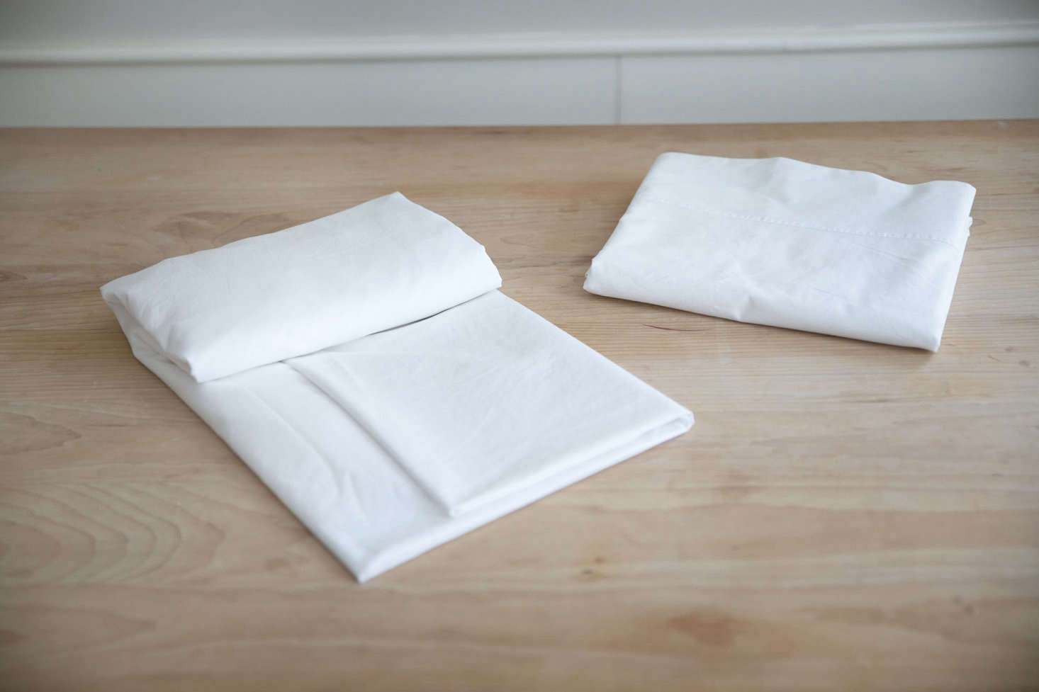 Fold the sheet neatly along the length, perhaps using a folded flat sheet as a guide so that they match sizewise.