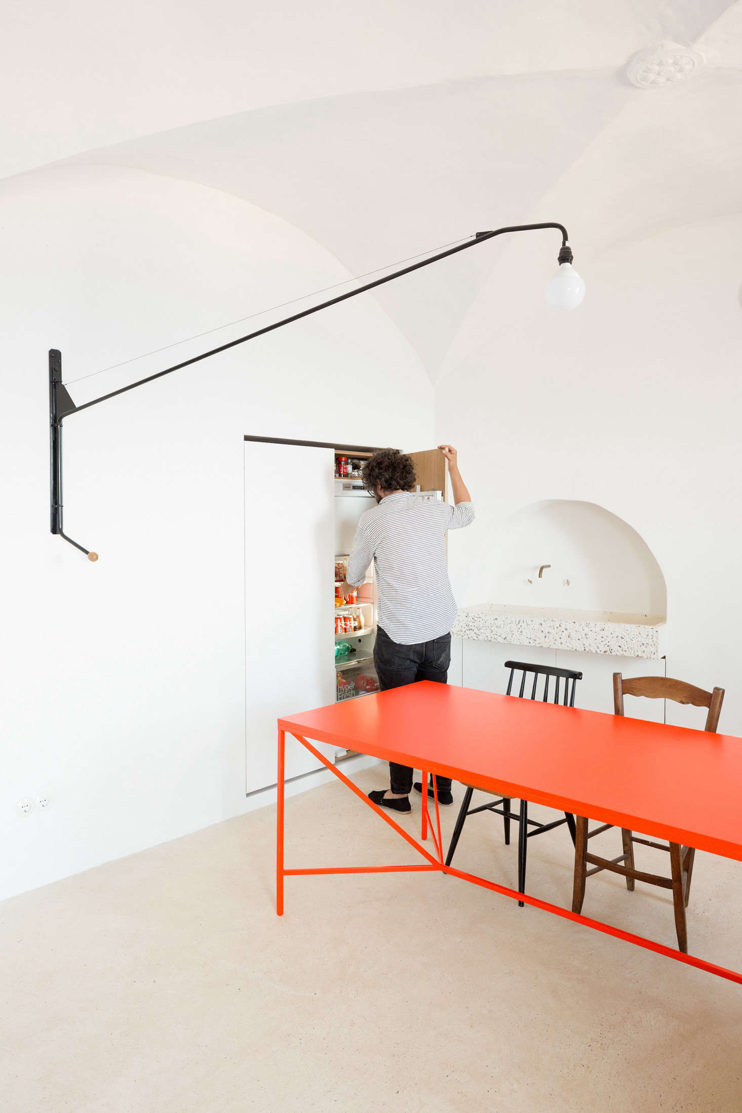 To the left of the dining table, the architects enlarged an existing niche to fit—behind the righthand door—a fridge and freezer and—behind the lefthand door—a washing machine, electric oven, and food storage. 