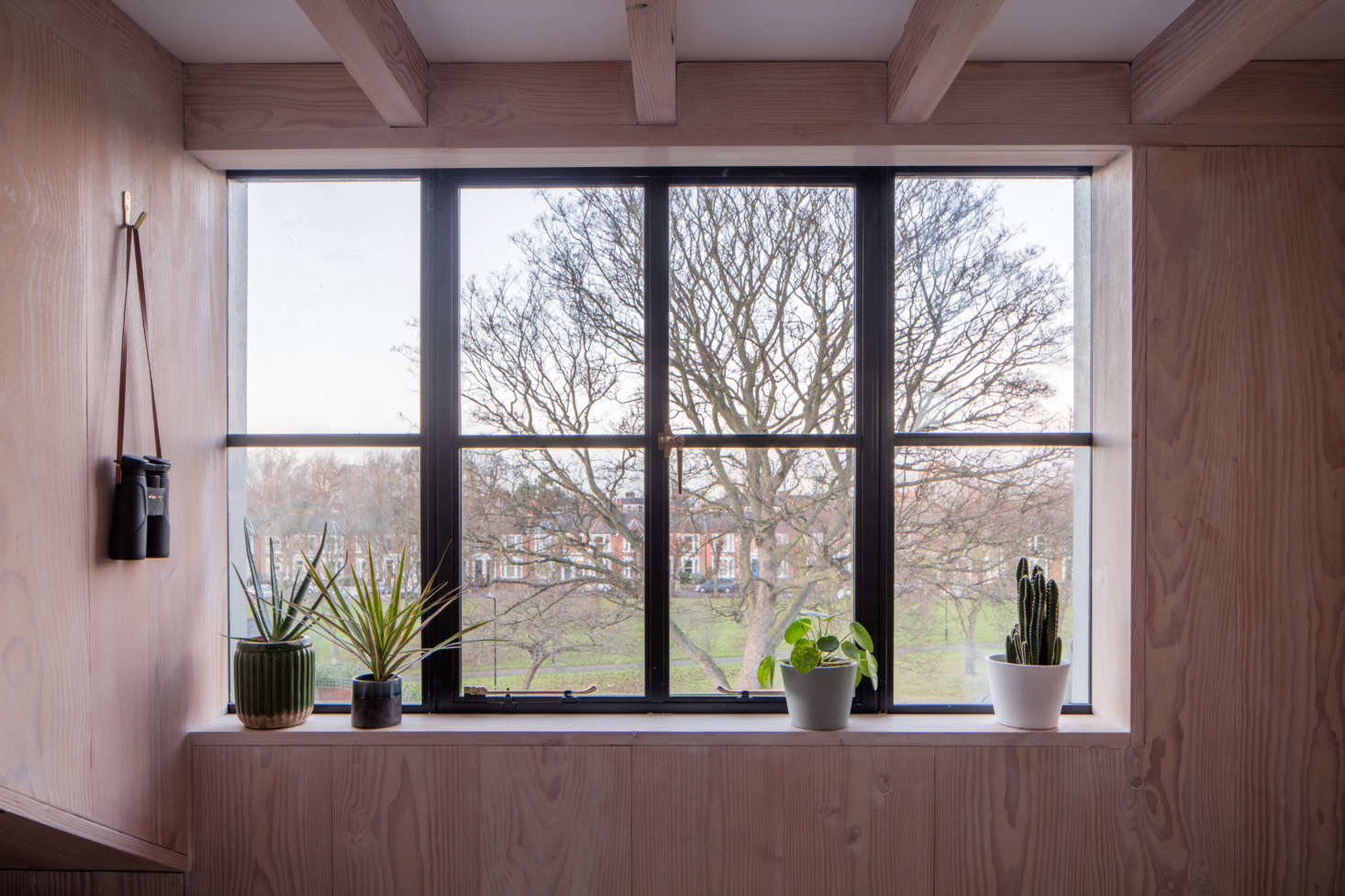 An upstairs window with a generous sill for plants. The wall hook is the Solid Brass Hook With Polished Edge, currently unavailable from Etsy shop Atifakuto.