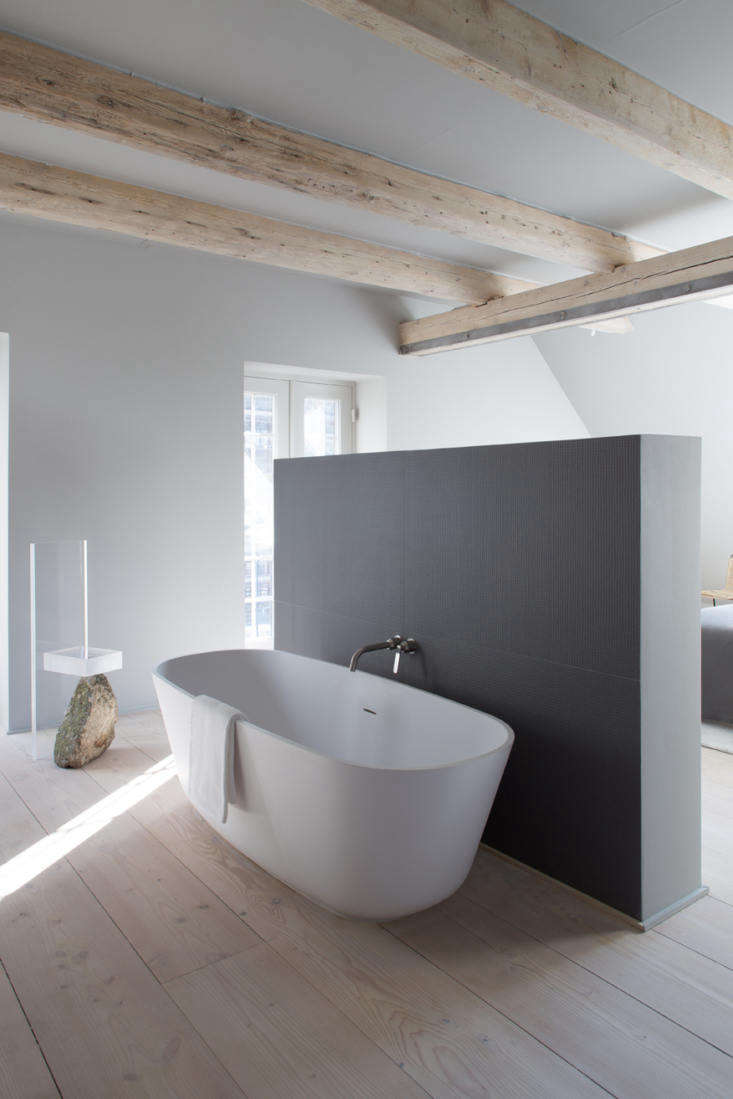 a free standing oval tub is tucked in the bathroom behind a privacy wall. 26