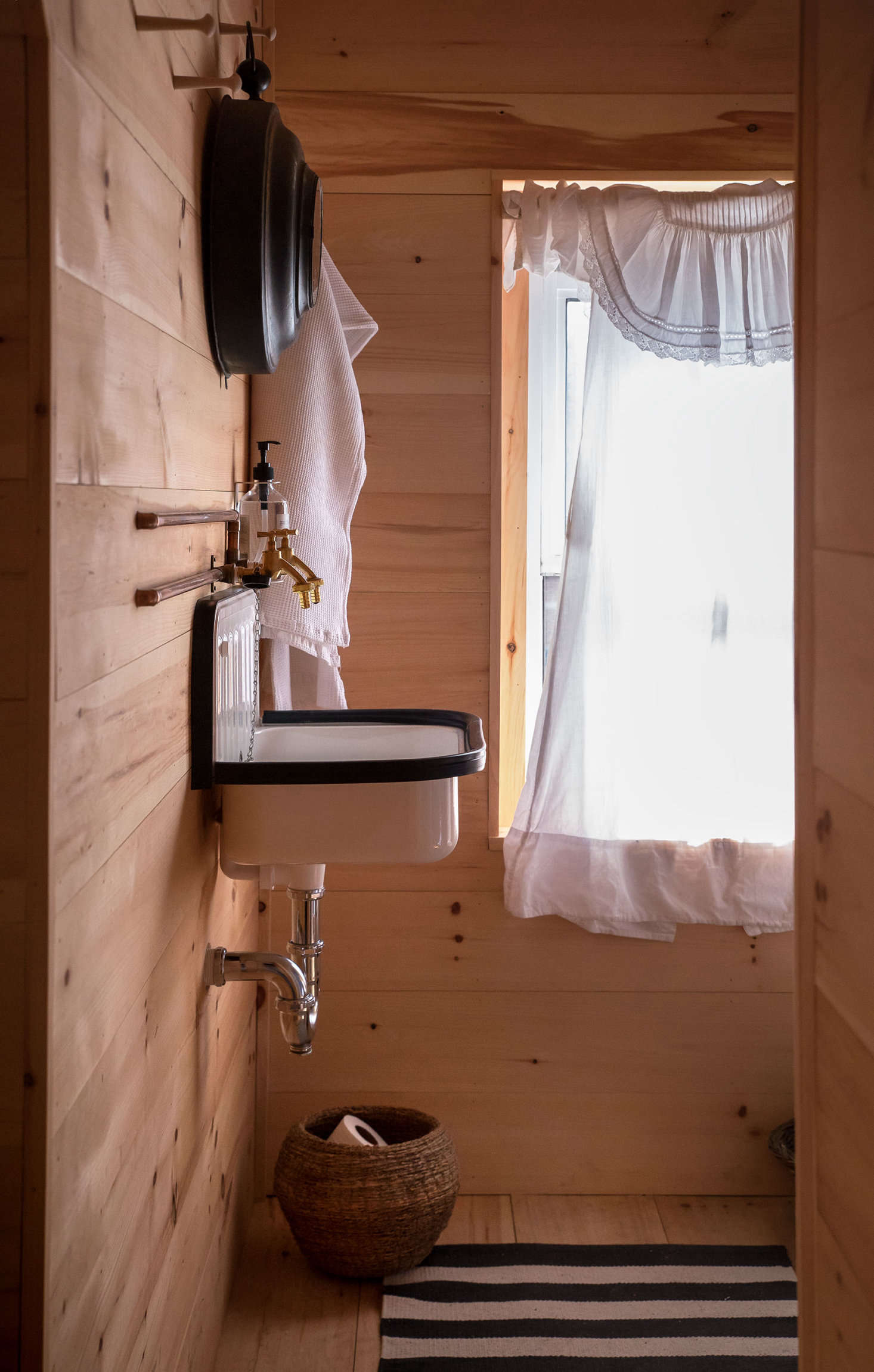 Under the attic eves, Sharon and Paul established rustic, camp-like accommodations for guests, including this bathroom with custom faucets that Paul fashioned with hardware from a garden supply shop. Note also the use of vintage nightgown as curtain.