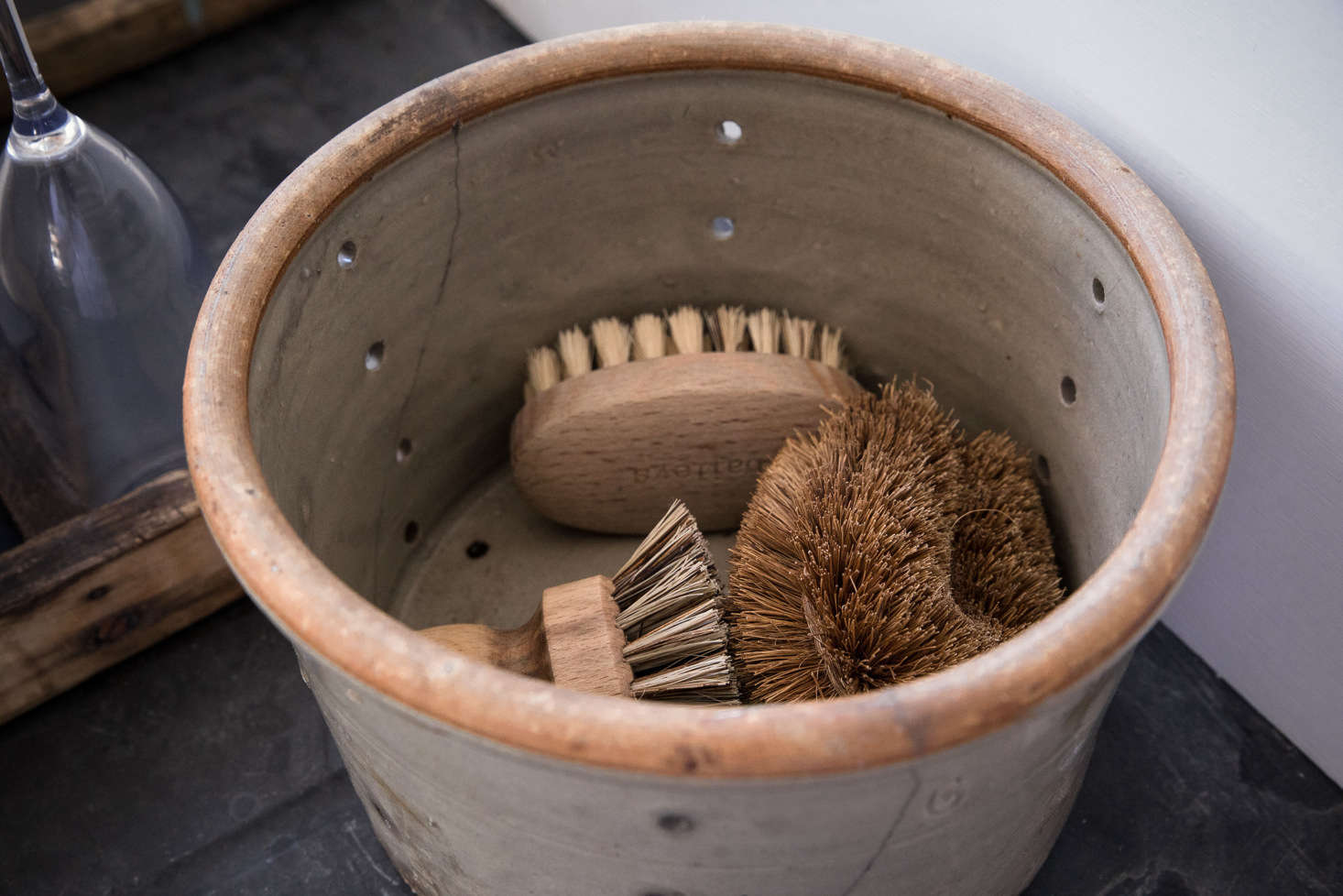 Next to the sink, a vintage pot houses scrubbing brushes.
