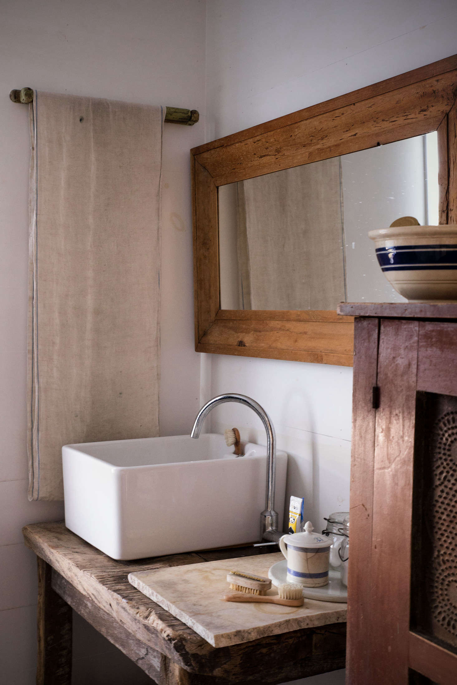 In the master bath, a Tuscan stand made from old farm boards supports a ceramic sink found at Baileys Home and Garden in England. The mirror is a striped, early pine ogee frame, circa 90.