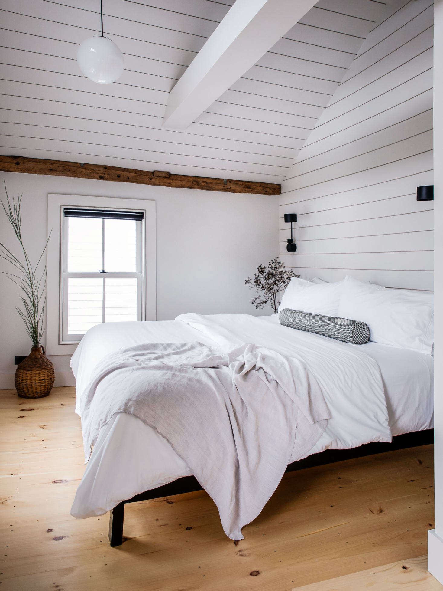 In the upstairs master bedroom, the couple also installed shiplap to accentuate the lofty ceiling. The pendant is Schoolhouse