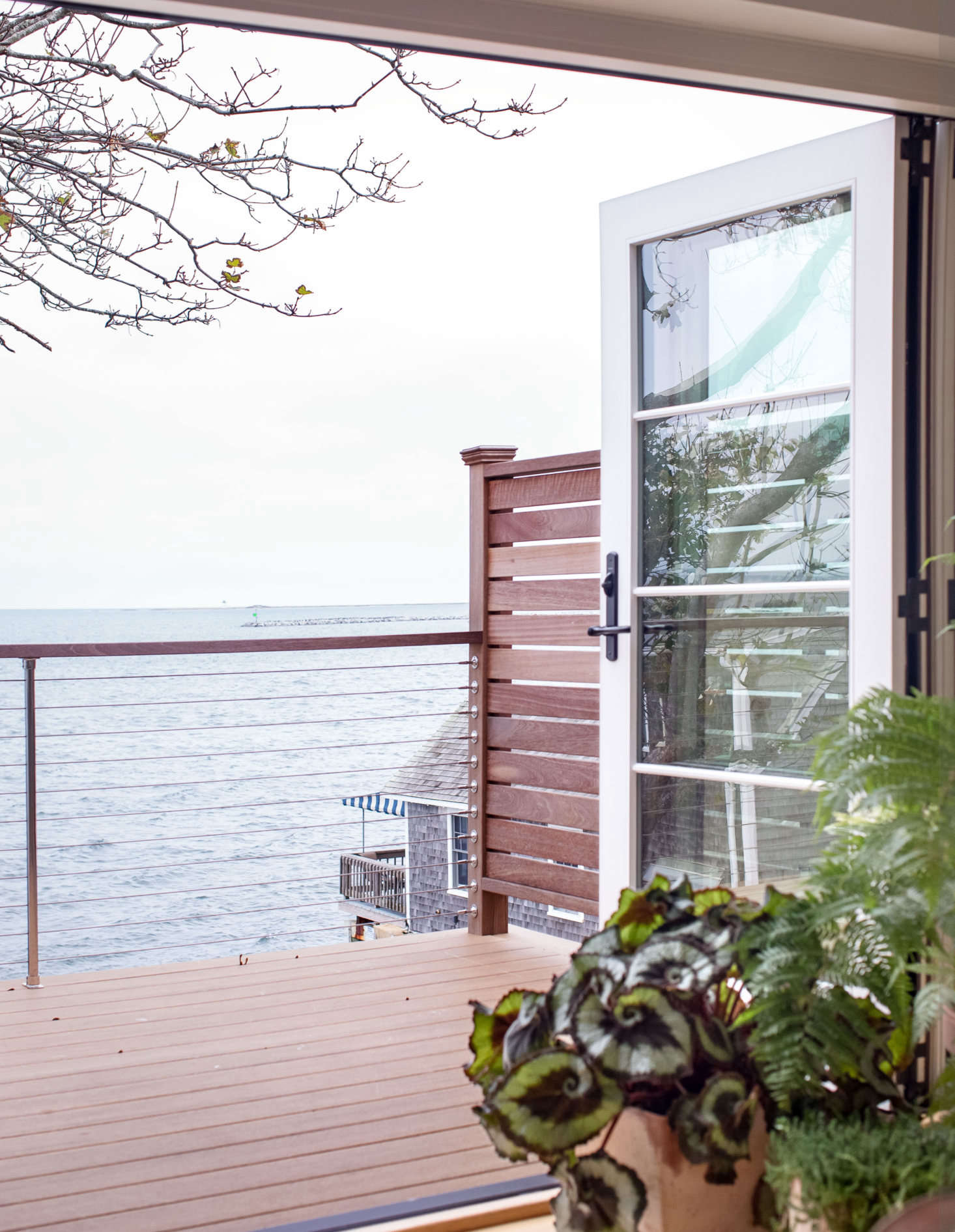 Accordion doors open fully onto the deck, blurring the lines between indoors and out. Here, clean marine accents like steel cable railings enhance the updated nautical feel.