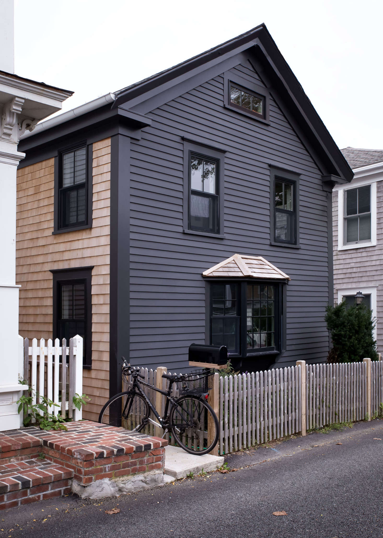 The exterior features traditional shingle and clapboard siding updated with a more modern noir hue: Benjamin Moore