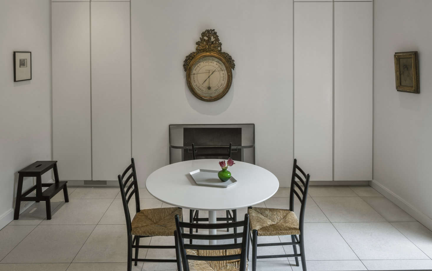 The kitchen table came from West Elm and the rush chairs are a vintage Gio Ponti design that Mahlow bought on eBay. The fireplace replaced a space-hogging brick original; the new setup has a gas insert and is flanked by seamless storage cabinets. The carved-wood clock is Belgian.