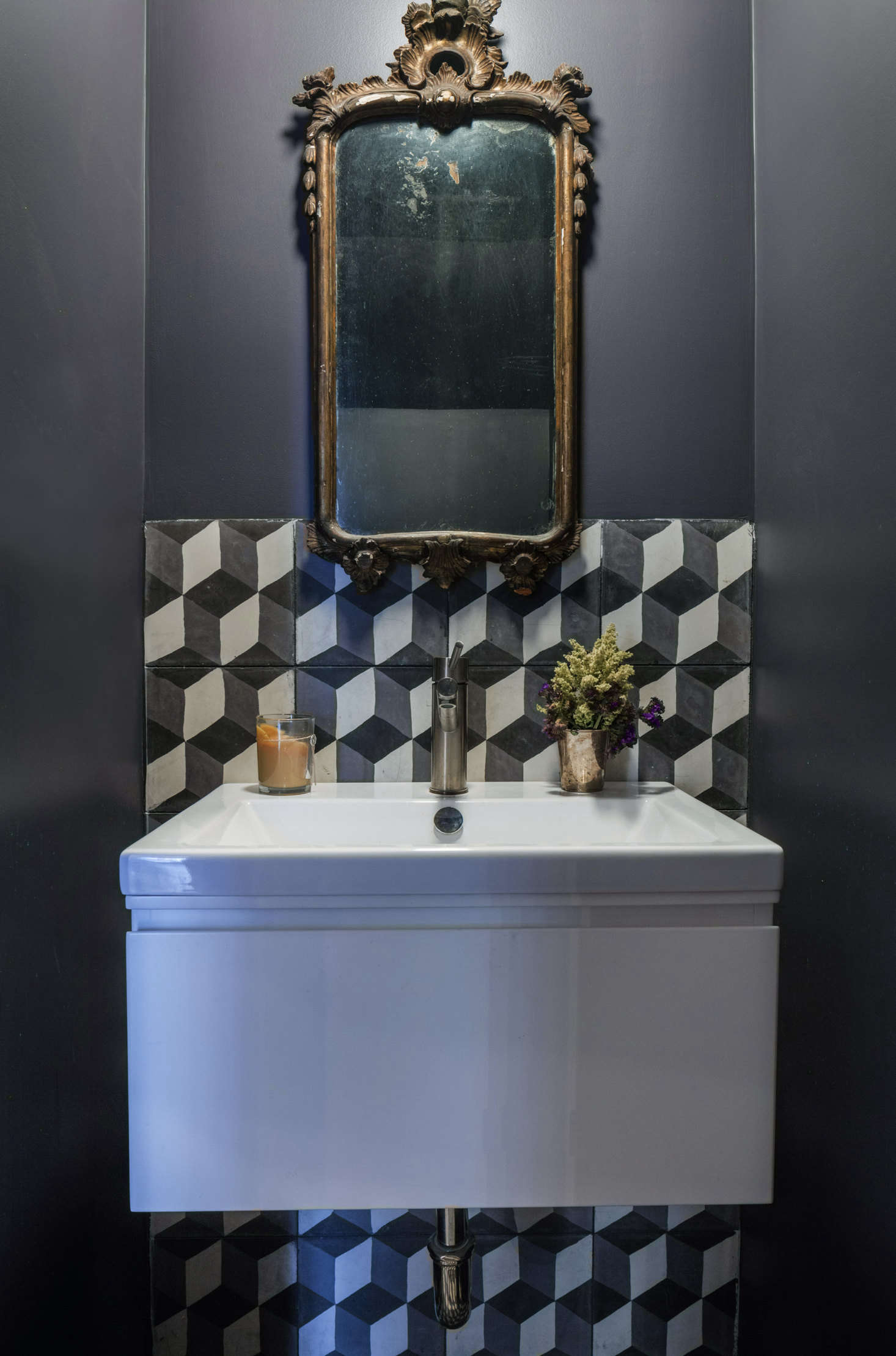 A new powder room tucked under the stairs has a cement-tiled backsplash in a pattern called Rotterdam Blocks from Granada Tile in Los Angeles. The sink is the