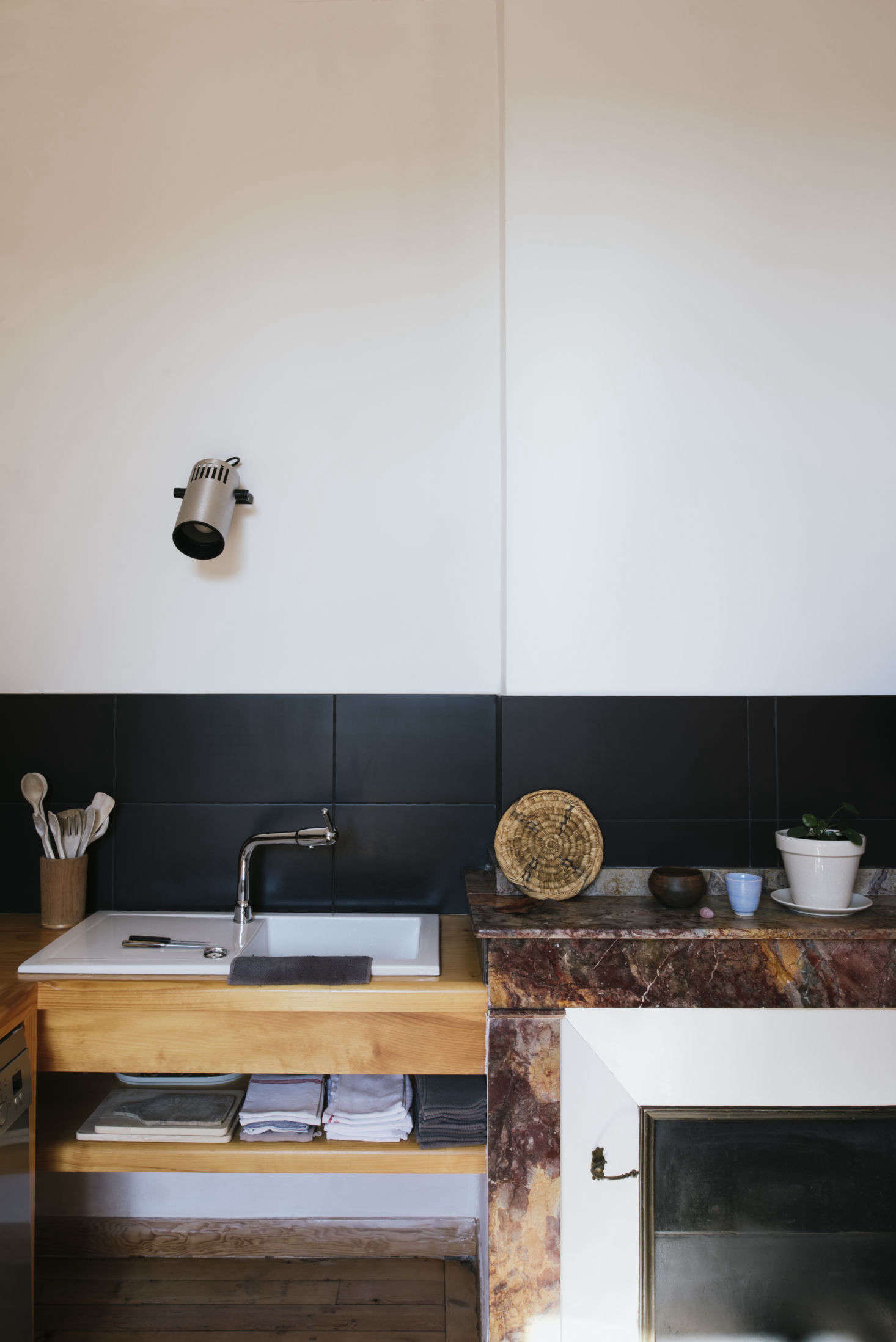 A sink, fitted into a wooden counter. Above it is an old projector light, a nod to Sathal