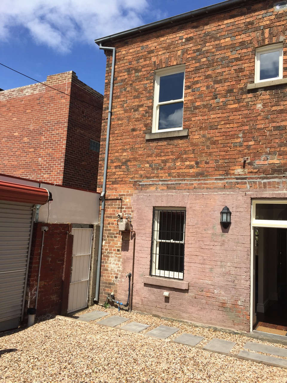 A metal garage door opened to a pebbled parking area.