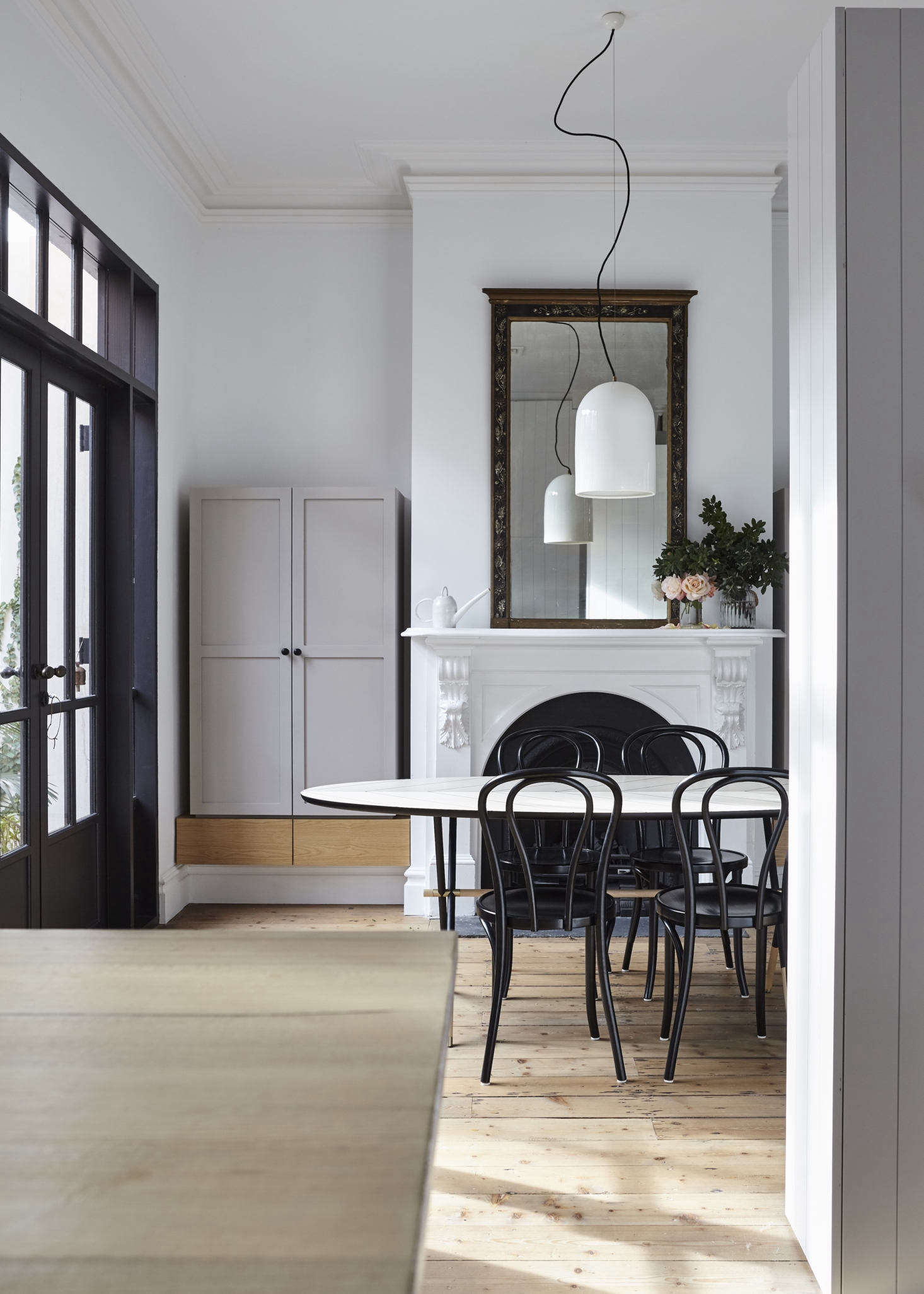 In the dining room, the original fireplace had been replaced by a modern version. Tom and Soma, in turn, replaced that with a mantel dating from the same period as the house. Whiting flanked it with storage cabinets in Dulux