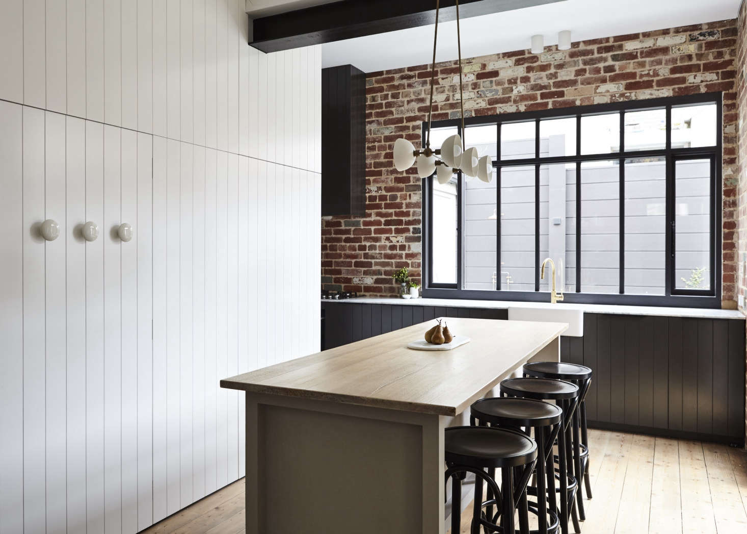 Whiting applied clean white ceramic details as a repeating element: the Porcelain Cabinet Handles, shown here on the paneled door to the WC-laundry, are by Danish ceramic artist Anne Black (they cleverly double as hooks and come in a range of colors and sizes). Apparatus Studio