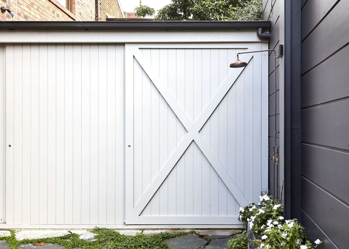 In place of a carport, the backyard now has a flagstone courtyard with a copper outdoor shower that gets used year round. The barn-door shed—made from the same style of paneling used indoors—holds bikes and gardening gear.