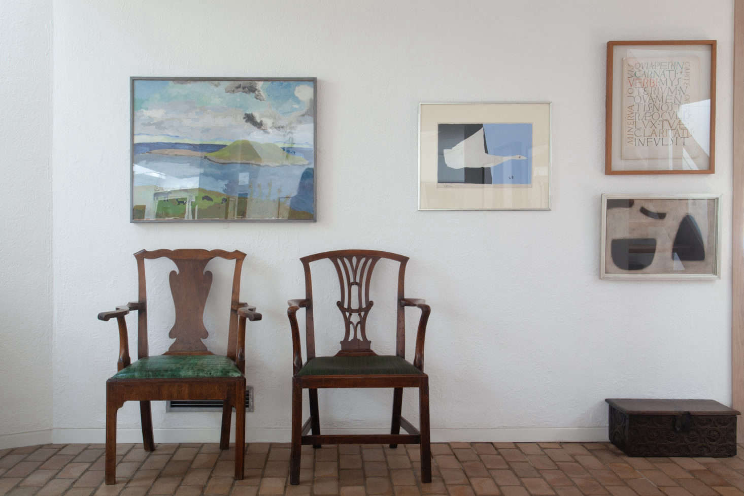 A pair of mismatched armchairs, both with green upholstered seats, are positioned in the gallery extension for guests to view paintings on the opposite wall.