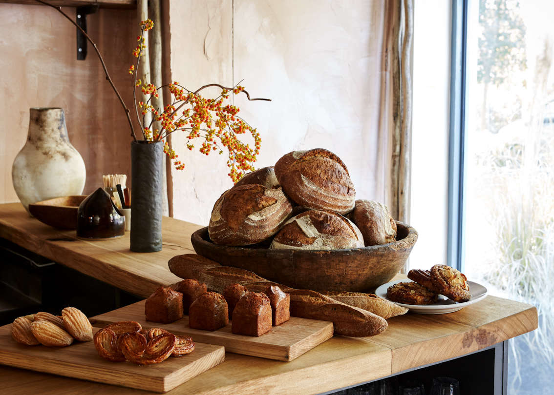 Madeleines, financiers, palmiers and Naroques bread made from French grains on the wooden counter.