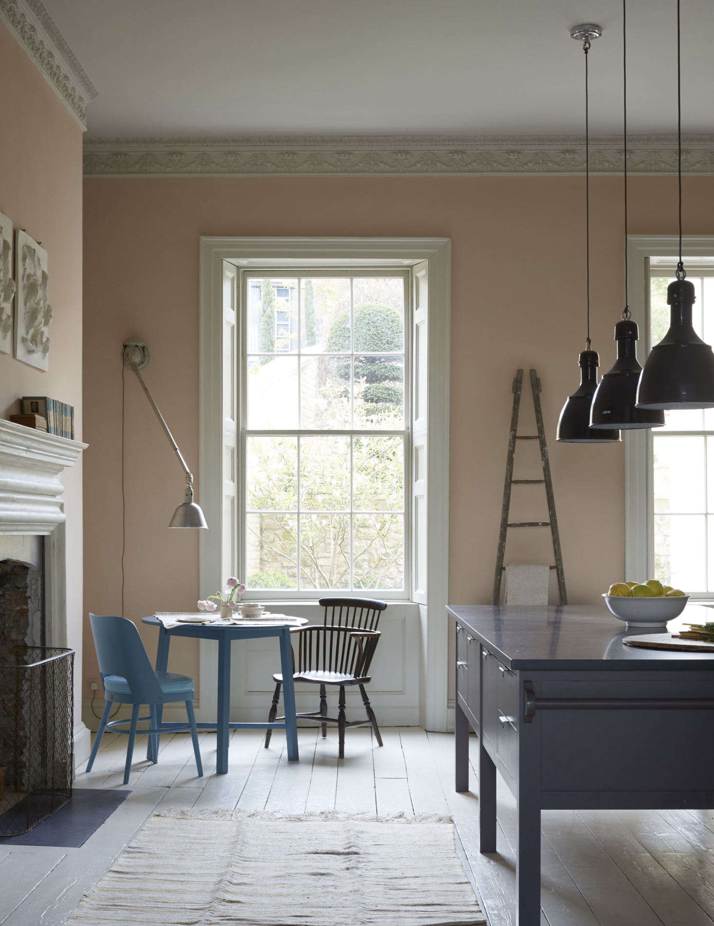 Invitingly small-scale, the breakfast corner is furnished with a Howe replica of an Arts and Crafts Round Oak Table and its Camembert Chair, both in a surprise bright blue. A French apple picking ladder is used as a sculptural dish towel rack.