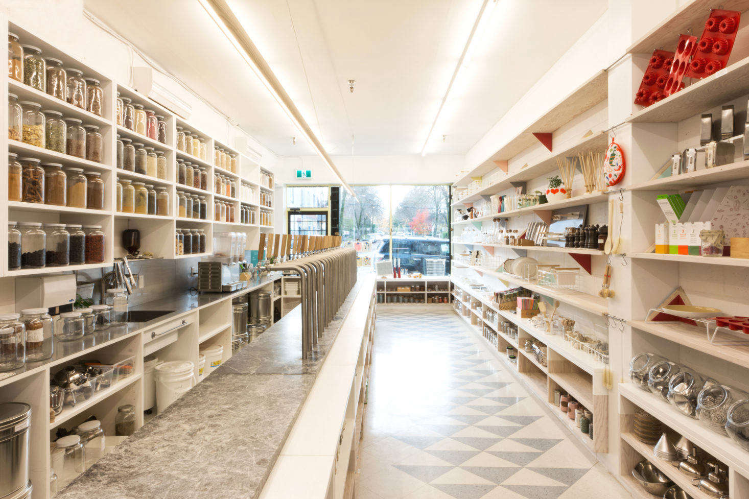 A single dispensing bar bisects the narrow space. The Scotts designed a 7-meter-long ash dowel pendant light, suspended above the bar with washing line, to coordinate with the oiled ash taps that dispense oils, syrups, and vinegars.