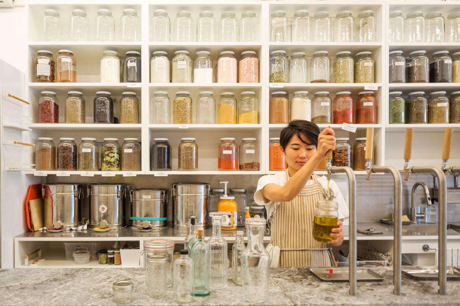 A shop assistant refills cooking oil for a customer. 