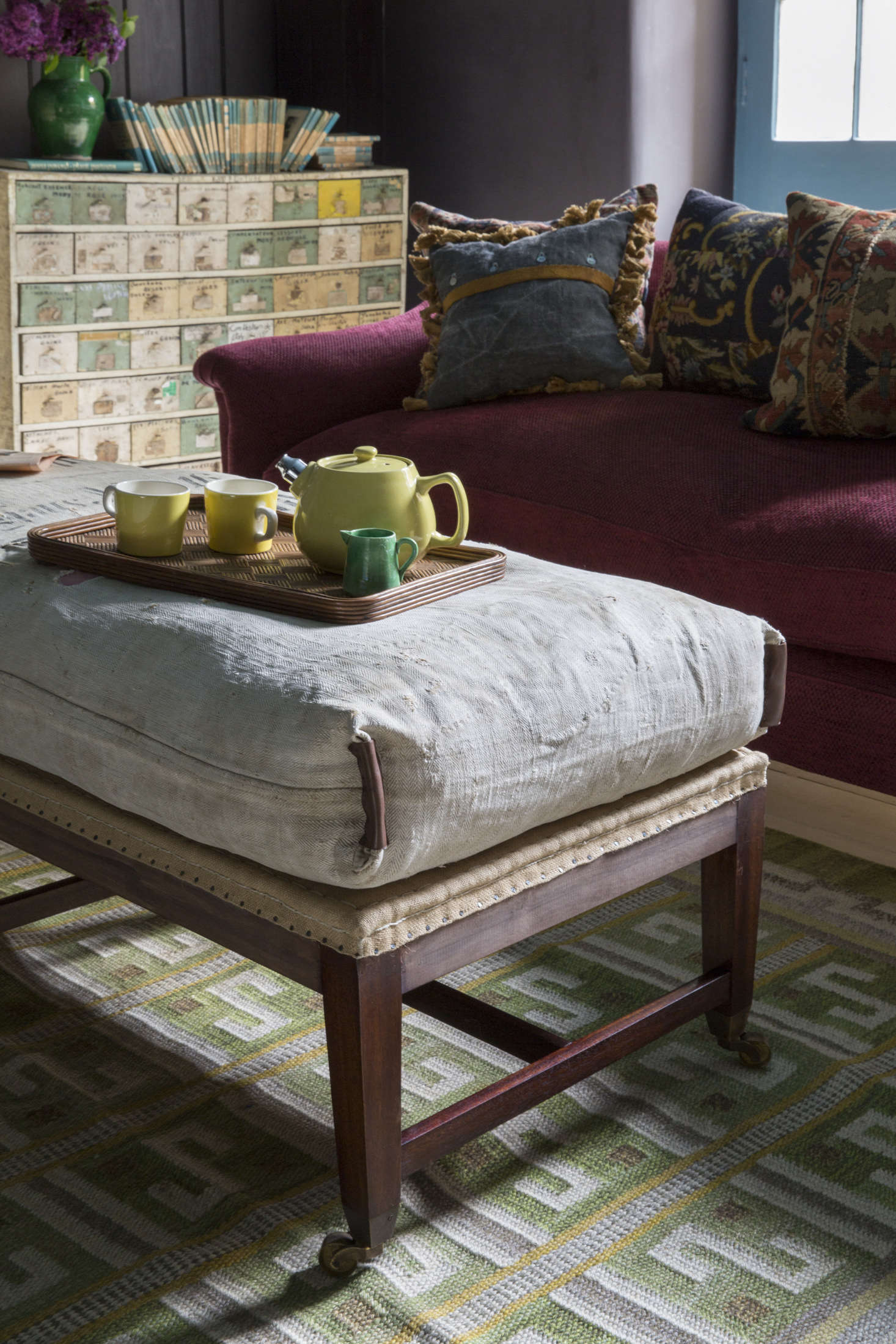 A Howe bestseller, the deconstructed Gainsborough Stool, serves as a seat, footrest, and coffee table. Howe says the set of painted drawers next to the fireplace came out of a Vespa shop in France with labels intact. They