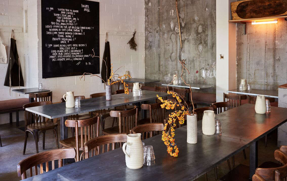 “Incandescent strip lights have become our signature,” explains Jeremie. They have been phased out of production across Europe so it took nine months to source these from Atlanta (Jeremie has 300 spares in storage). Here, they are positioned under a high shelf that displays a rustic Hungarian meat trough for corralling produce.