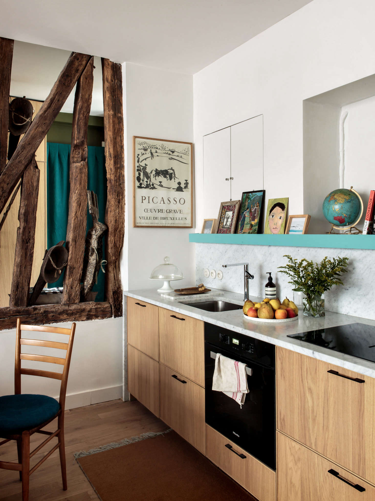 The kitchen is composed of Ikea Ekestad cabinets that Hermand customized with a marble counter and backsplash. Existing wall niches were incorporated as storage and display.