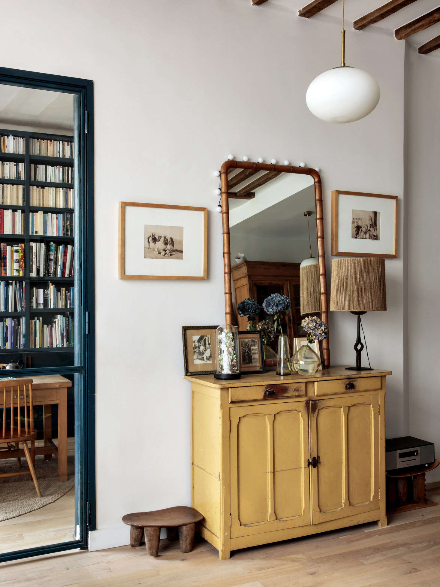 An ensemble of flea market pieces: Hermand frequents the St. Ouen Marché aux Puces. She uses African stool as low tables. The steel door frame is in a powder-coated blue to match the library.