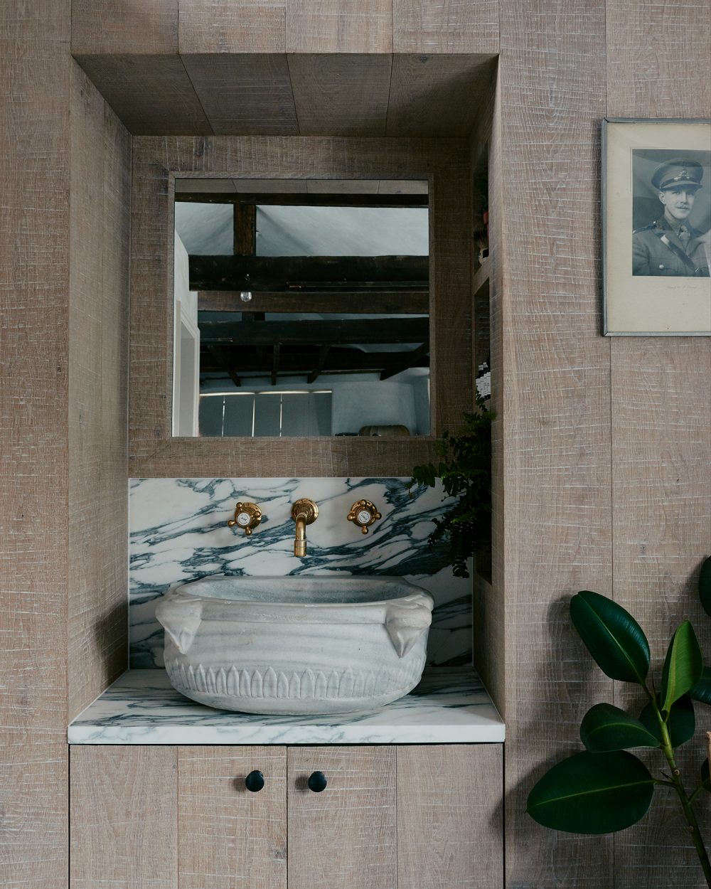 A dramatic slab of Arabescato marble anchors the antique carved stone sink. Photography by Michael Sinclair, courtesy of Chan + Eayrs from The Design Is in the Details: The Weavers House, Chan + Eayrs’ Huguenot-Inspired Oasis in London.