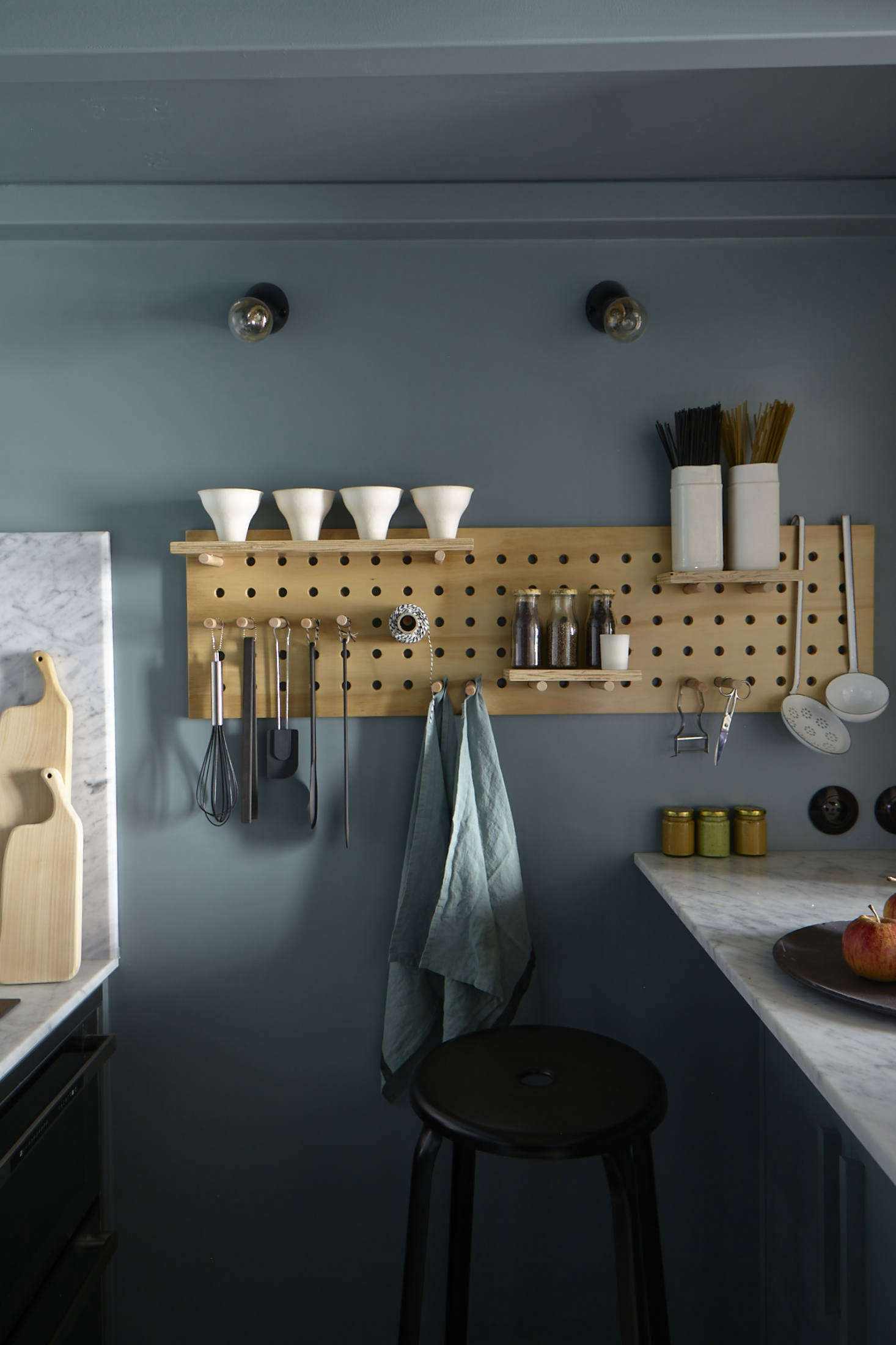 A pegboard makes use of the small space and keeps tools, towels, and twine within easy reach. The flush-mount light bulbs are from Zangra.