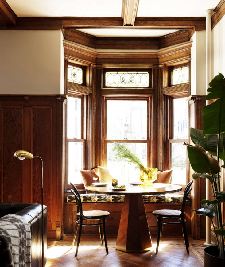 caned chairs flank a breakfast table, set into a bow window. the stained glass  24