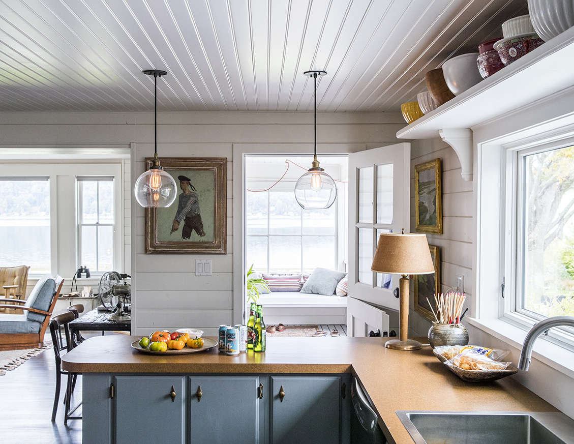 The only element that survived the renovation? The 50s kitchen cabinets, now painted a gray-blue and appointed with brass hardware for a nautical feel. Formica countertops (new) further the old beach-cottage story.