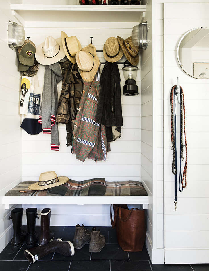 The hardworking mudroom, complete with sturdy hooks; a round porthole-like mirror; a nautical cleat door handle (and improvised leash holder); and industrial nautical sconces. (See Nautical Hardware: 7 Cleats for Home Use.)