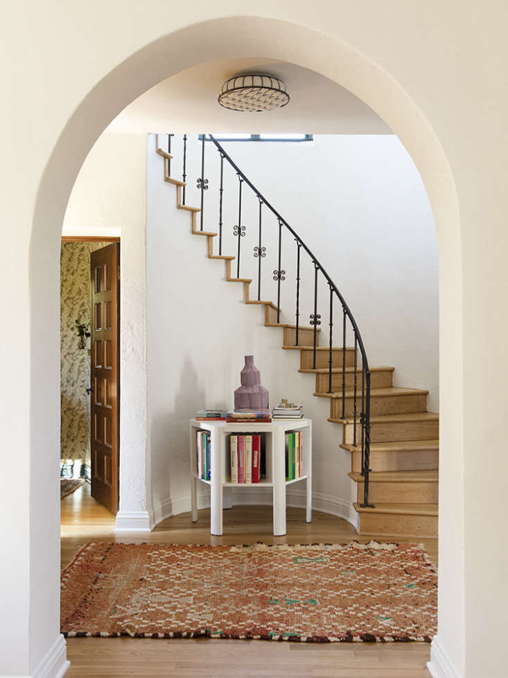 a martin & brocket library table stands in the entry under a curved stair.  18