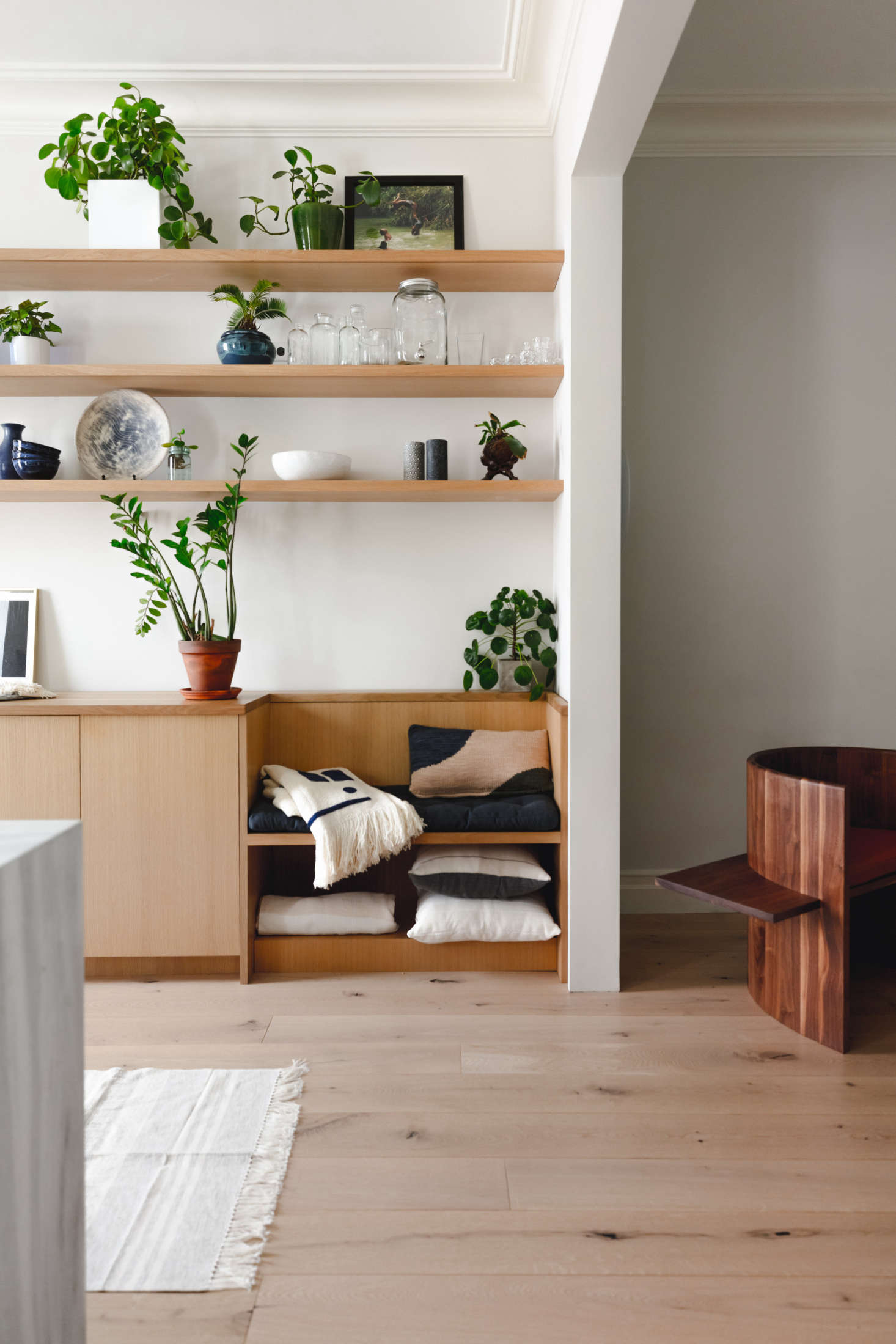 The architects inserted a little bench next to the cabinets (cushioned with pillows and throws from Minna). Of the couple