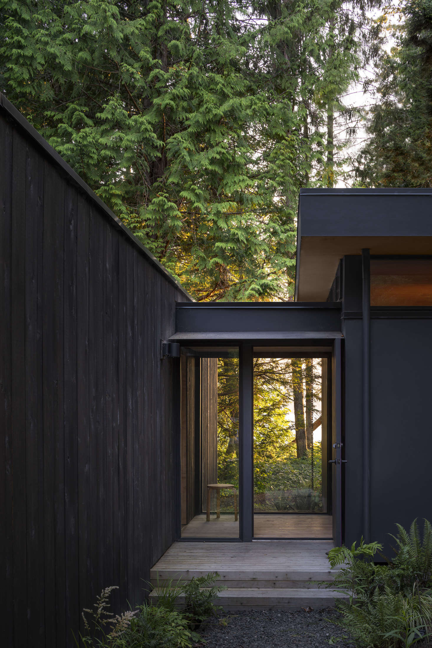 A glass vestibule connects the original main cabin to the new addition, which now houses a bedroom and bathroom. The rough-sawn cedar siding is unpainted to encourage natural aging.