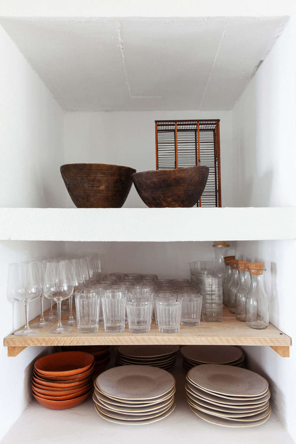 Shelves hold stacks of cream and terra cotta-colored dinnerware.