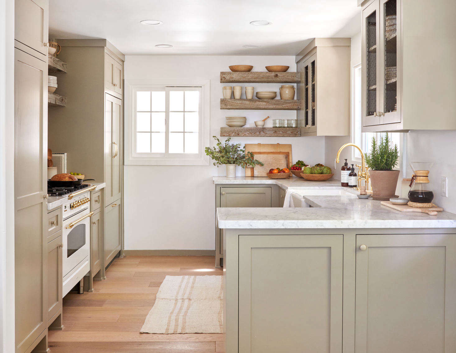 The team re-envisioned a dark and cramped kitchen into a compact but open-feeling space. The cabinets are custom, made by a local carpenter and painted in a subtle earthy tone, Farrow & Ball