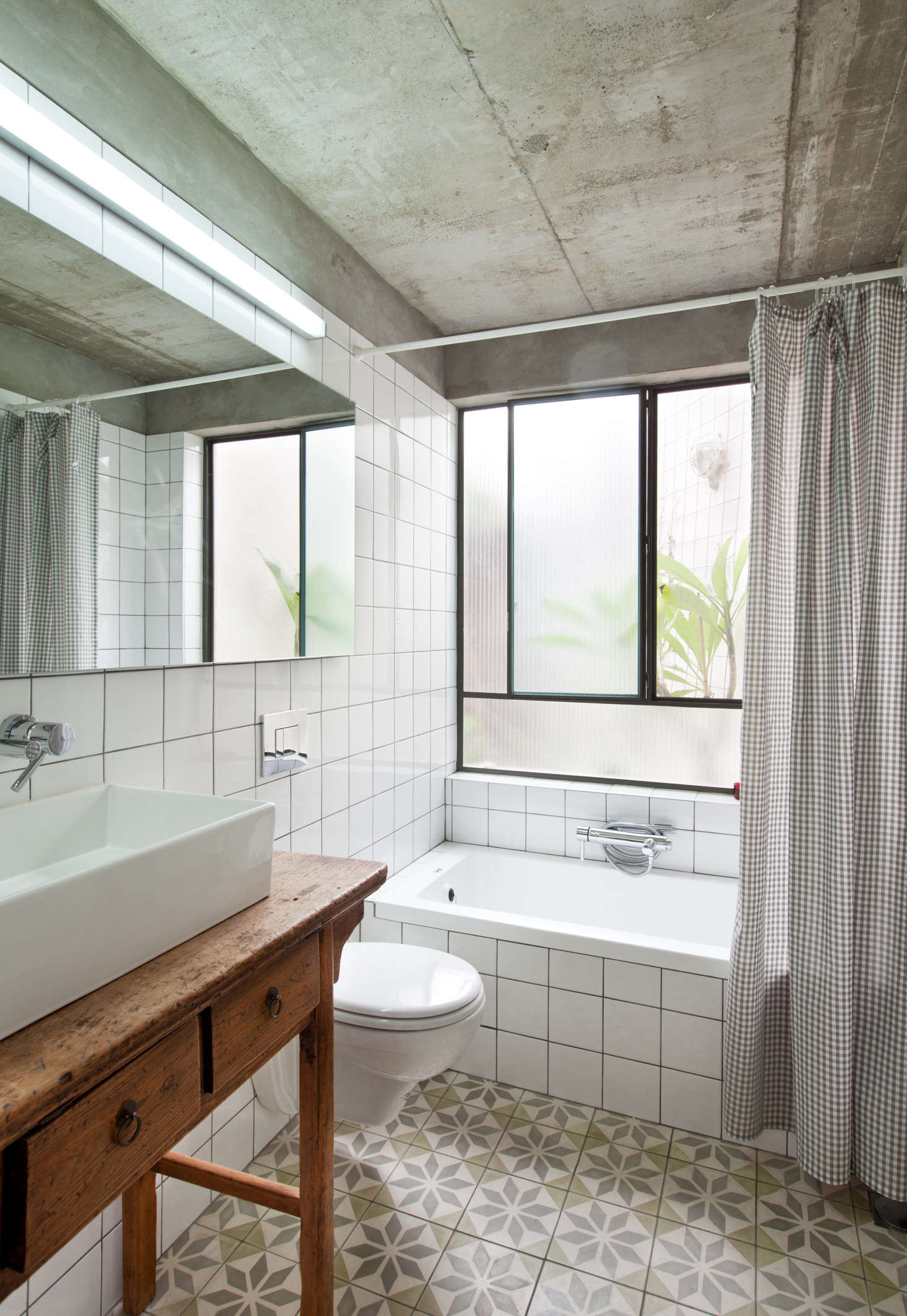 The guest bathroom was gutted and re-built with a bare concrete ceiling and bath. A rustic table from Primitive and Design serves as a vanity.