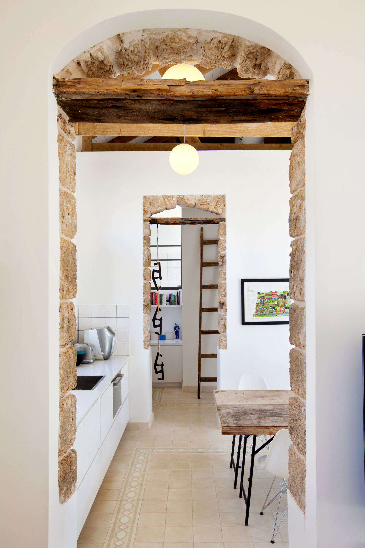 Twin archways lined with original stone lead into the simple white kitchen.