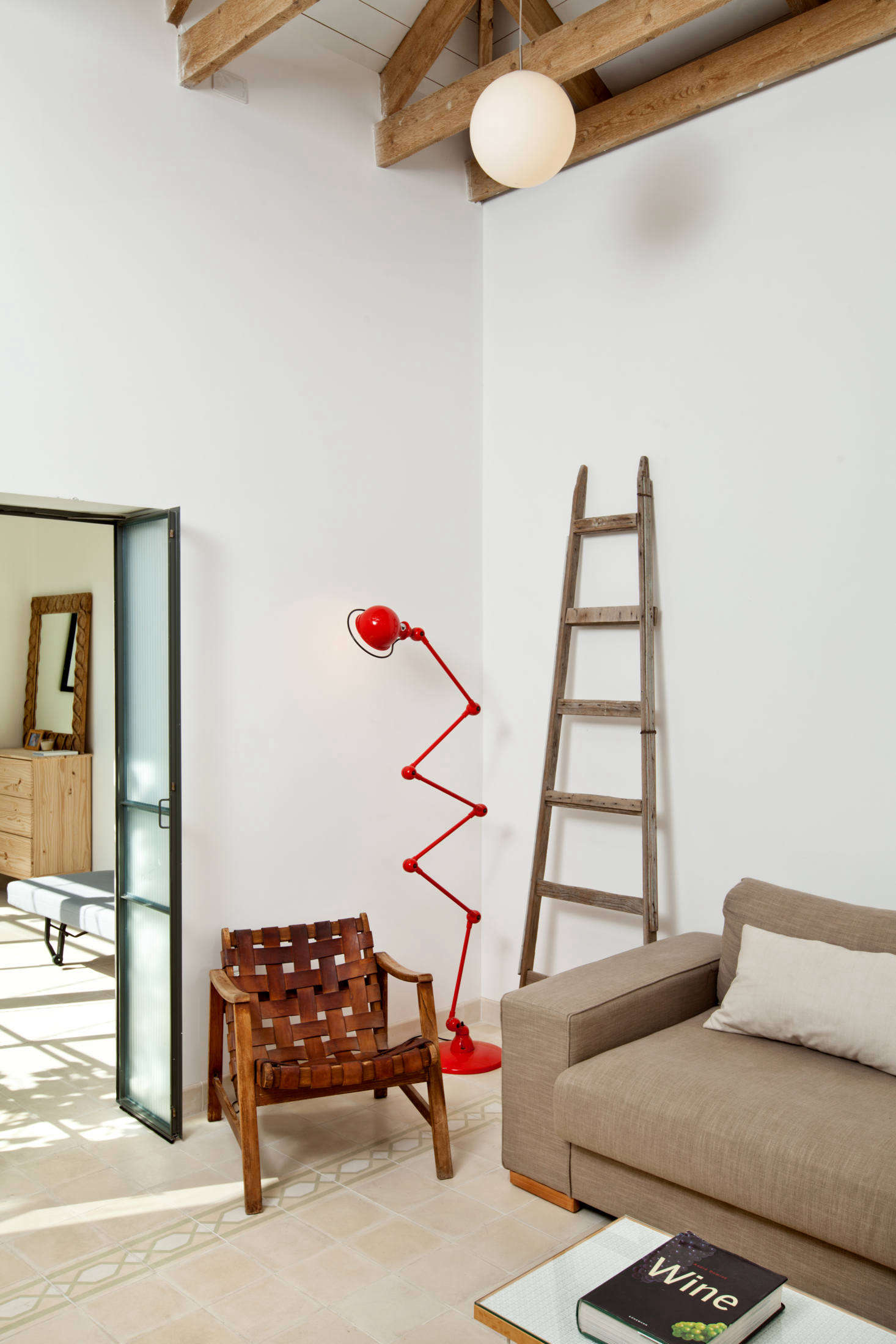 A red standing lamp adds an unexpected jolt of color to the otherwise-neutral sitting area. The lighting throughout is from Israeli company Dori Kimhi.