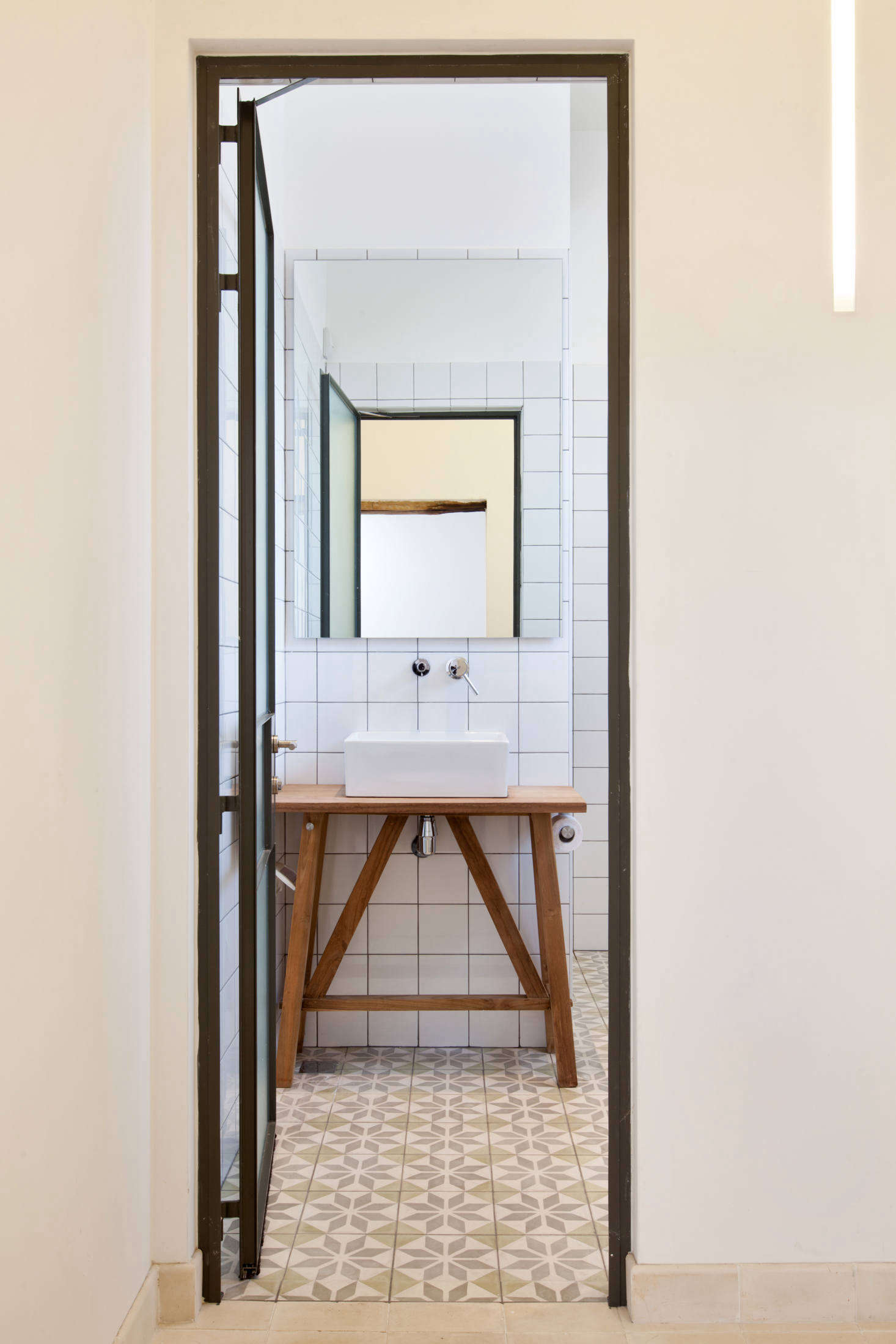 The master bath is fitted with painted tiles from Gluska and a steel-frame door.