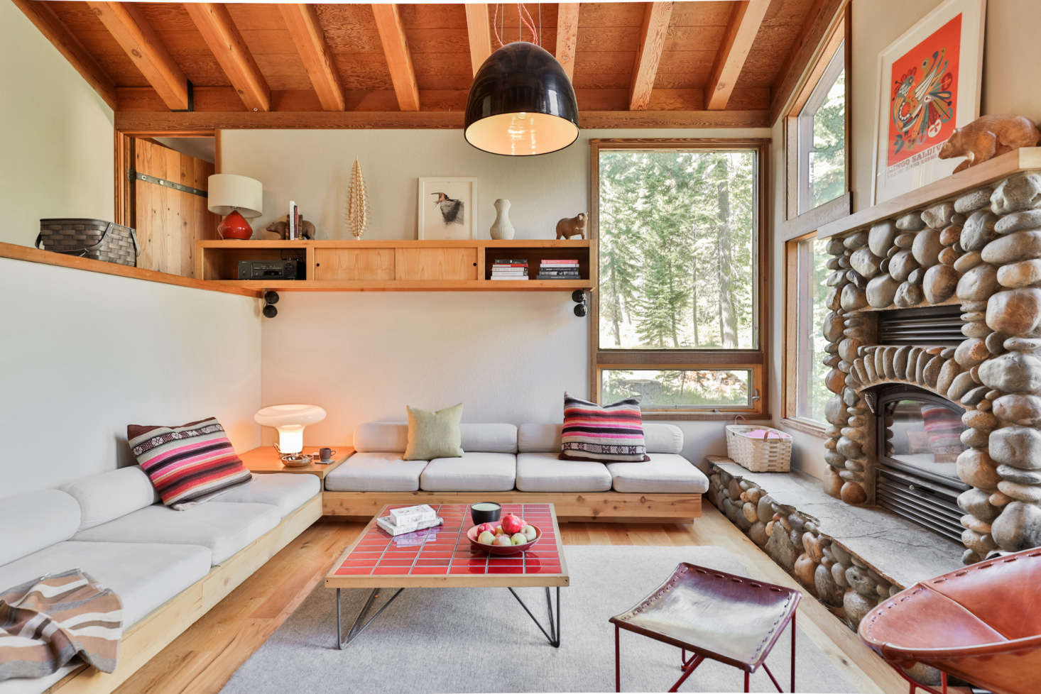 The living room features low-slung seating for gathering around the stone fireplace.
